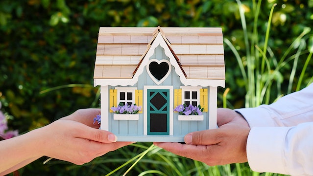 two sets of hands holding up a toy house